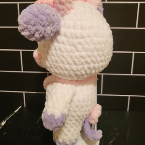 Back view of the completed amigurumi pattern project, showing the seamless color changes and attachment points for the removable satchel bag.