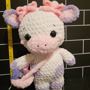 Profile of the crocheted cow, demonstrating the final shape and size (approx. 10 inches) for buyers interested in the amigurumi stuffed animal pattern.