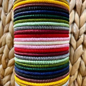 May include: A stack of 24 colorful braided elastic hair ties in various colors including red, green, blue, yellow, and white.