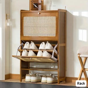 May include: A wooden shoe rack with a woven front panel and multiple shelves. The rack is filled with white and beige shoes. A clock and decorative items sit on top. The rack is designed to store shoes and keep them organized.