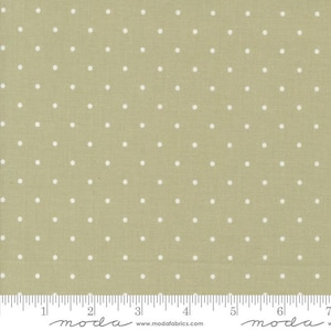 May include: A fabric swatch featuring a light olive green background with a repeating pattern of small, evenly spaced white polka dots. The fabric has a textured appearance and a ruler is at the bottom.