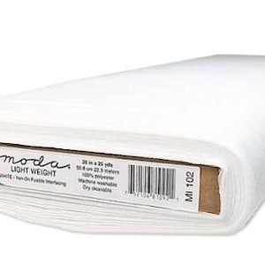 May include: A roll of white, lightweight, non-woven interfacing fabric. The label reads "moda LIGHT WEIGHT" and includes details about the fabric's dimensions, material, and care instructions. The roll measures 20 inches by 25 yards.