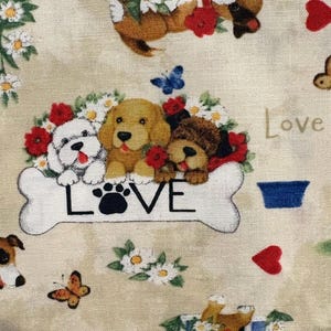 May include: A beige fabric featuring a repeating pattern of puppies, red hearts, blue butterflies, and white daisies. A large white bone shape displays the text LOVE with a black paw print replacing the letter O, surrounded by three puppies.