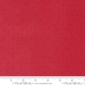 May include: Red fabric with small, evenly spaced brown dots. The fabric has a textured appearance and is shown with a ruler along the bottom edge. The fabric is from Moda Fabrics.