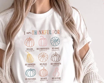 May include: White t-shirt with the text "I am THANKFUL FOR" and colorful pumpkin illustrations. The shirt lists various blessings such as love, forgiveness, and grace. The shirt is made of Bella+Canvas 3001 material.