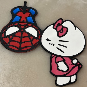 May include: A red and black Spider-Man character with a blue and red mask is kissing a white Hello Kitty character with a pink bow and pink dress.