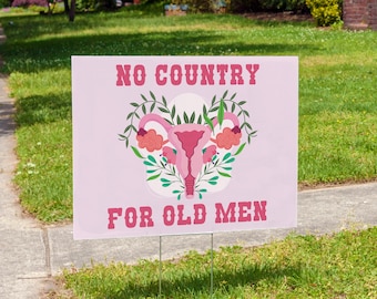 May include: Pink yard sign with the text "NO COUNTRY FOR OLD MEN" and a stylized illustration of a uterus with flowers.
