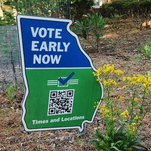 May include: A die-cut yard sign shaped like the state of Georgia, featuring a blue top section with white text reading VOTE EARLY NOW and a green bottom section with a white checkmark icon, a QR code, and the text Times and Locations.