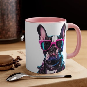 May include: A white ceramic mug with a pink rim and handle. The mug features a colorful illustration of a French bulldog wearing pink sunglasses and a black leather jacket.