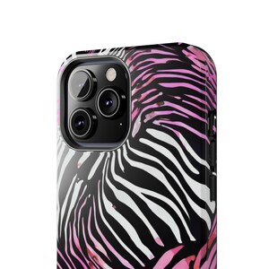 K&ouml;nnte beinhalten: Nahaufnahme einer Smartphone-H&uuml;lle mit Zebramuster. Die H&uuml;lle hat ein Muster in Schwarz, Wei&szlig; und Rosa. Die Kameralinsen des Telefons sind auf der oberen linken Seite zu sehen.