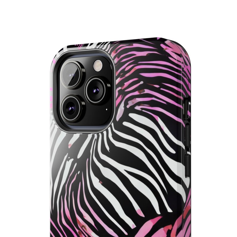 K&ouml;nnte beinhalten: Nahaufnahme einer Smartphone-H&uuml;lle mit Zebramuster. Die H&uuml;lle hat ein Muster in Schwarz, Wei&szlig; und Rosa. Die Kameralinsen des Telefons sind auf der oberen linken Seite zu sehen.