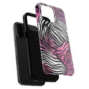 K&ouml;nnte beinhalten: Ein schwarzes Smartphone mit einer schwarzen H&uuml;lle und einer separaten H&uuml;lle mit einem Zebra-Print-Design in Schwarz, Wei&szlig; und Pink. Das Telefon und die H&uuml;llen werden vor einem wei&szlig;en Hintergrund gezeigt.