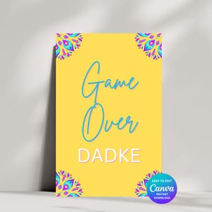 May include: A yellow printable sign with the text "Game Over Dadke" in blue and pink. The sign is decorated with colorful mandala designs in the corners. The text "Easy to edit Canva Instant Download" is in the bottom right corner.