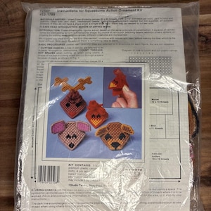 May include: A sealed plastic bag containing a craft kit. The kit includes instructions and materials for creating dimensional Squeezums action ornaments. The package features images of finished ornaments, including a reindeer, bird, mouse, and dog.