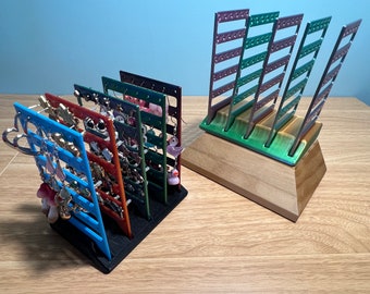 May include: A set of five colorful earring stands with a variety of earrings displayed. The stands are made of plastic and have a black base. The stands are arranged in a row on a wooden surface.