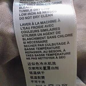 May include: A white fabric care label with black text in English, French, and Chinese. The instructions read: MACHINE WASH COLD WITH LIKE COLORS, USE ONLY NON-CHLORINE BLEACH, TUMBLE DRY LOW, LOW IRON AS NEEDED, DO NOT DRY CLEAN, and laundry symbols.