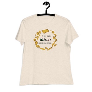 May include: A beige t-shirt with a graphic of pasta shapes surrounding the text "Is she even Italian? Her name is Bella."