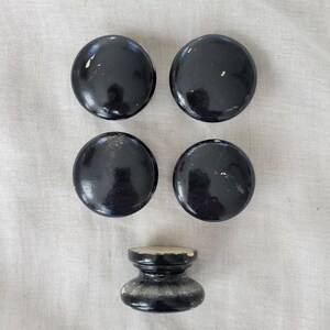 May include: Five black wooden knobs, four are round and one is a round knob with a raised base.