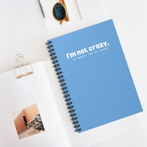May include: A blue spiral notebook with the text "I'm not crazy, my mother had me tested" in white.