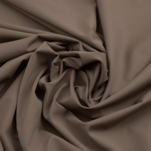 May include: Close-up of a fabric with a smooth, matte finish. The fabric is a solid, muted brown color, with soft folds and subtle shadows. The material appears to be a medium-weight textile, suitable for apparel or home decor.
