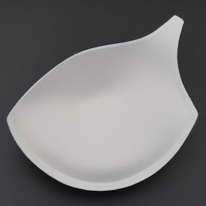 Könnte beinhalten: Weißer Schaumstoff-BH-Einsatz. Der Einsatz ist halbkreisförmig und hat eine glatte, nahtlose Oberfläche.