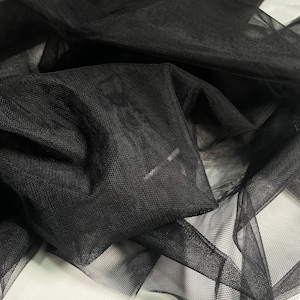 May include: Black tulle fabric with a fine mesh texture. The fabric is soft and delicate, and it is perfect for a variety of crafting projects.