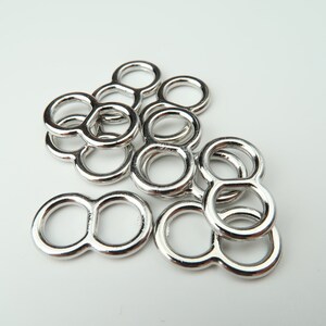May include: A group of silver-toned metal rings with a figure eight shape. The rings are stacked on top of each other.