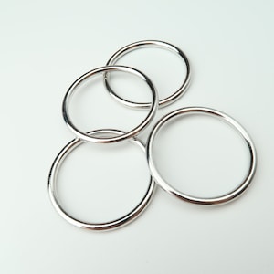 May include: Four silver metal rings of different sizes, stacked on top of each other.