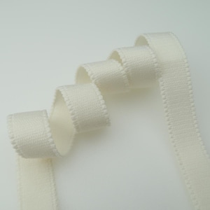 May include: White elastic trim with a scalloped edge. The trim is folded and coiled on a white background.