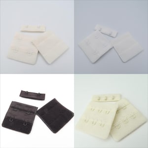 Op de afbeelding: Vier sets bh-bandverlengers. Twee sets zijn wit, één is zwart en één is beige. Elke set bevat twee vierkante stukken met haken en ogen, en een klein rechthoekig stuk met haken.