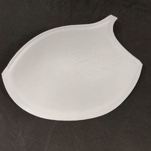 Puede incluir: Inserción de relleno de copa de sujetador blanco. La inserción está hecha de una tela suave y lisa y tiene una forma redondeada.