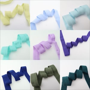 May include: Assortment of 10 colors of 1 inch wide elastic ribbon. The colors are: pale yellow, light blue, sky blue, mint green, lavender, purple, navy blue, olive green, teal green, and dark green.