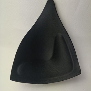 May include: Black bra cup padding insert. The insert is made of a soft, flexible material and has a curved shape to provide lift and support.