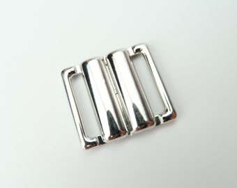 May include: Silver metal bra clasp with two loops.