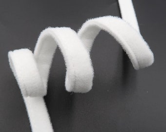 Puede incluir: Borde de tela blanco, suave y flexible, con una textura peluda. El borde está enrollado en forma de espiral.