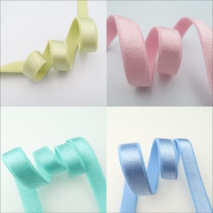 May include: Four spools of elastic ribbon in different pastel colors: light green, pink, light blue, and blue. The ribbon is soft and has a subtle sheen.