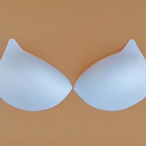 Puede incluir: Un par de insertos de sujetador de espuma blanca. Los insertos tienen forma de semicírculo y están diseñados para agregar volumen a un sujetador.