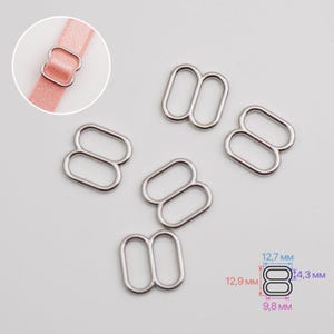 May include: Five silver-colored metal bra strap sliders with a rounded rectangular shape. A circular inset shows one slider on a pink strap. A technical diagram indicates dimensions of 12.7 mm by 12.9 mm by 4.3 mm by 9.8 mm for the hardware.