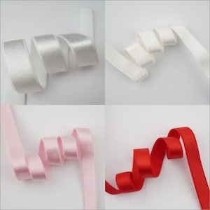 May include: Four spools of elastic ribbon in different colors: white, silver, pink, and red. The ribbon is folded and arranged in a decorative way.