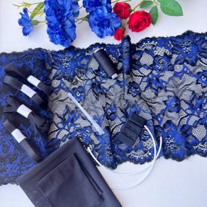 May include: A sewing kit for lingerie featuring a wide strip of black and royal blue floral lace, black elastic bands, a spool of black thread, black metal sliders, a black hook-and-eye closure, a plastic boning strip, and a piece of black fabric.