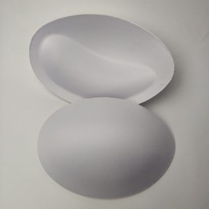 May include: Two white foam bra inserts, one is a half-cup shape and the other is a full-cup shape.