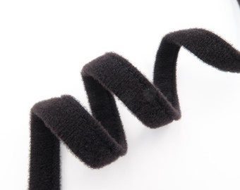 Puede incluir: Cinta de terciopelo negro enrollada sobre un fondo blanco.