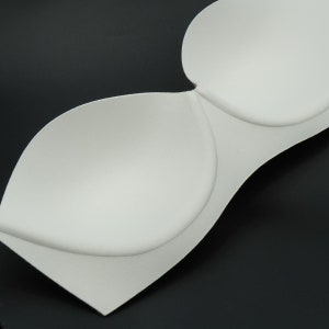 May include: White foam bra cups for sewing or crafting projects. The cups are made of soft, flexible foam and have a smooth, rounded shape.