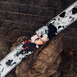 May include: Black and white leather belt featuring a graphic print of two anime characters. The characters are facing each other and their faces are partially obscured by a black and red design.