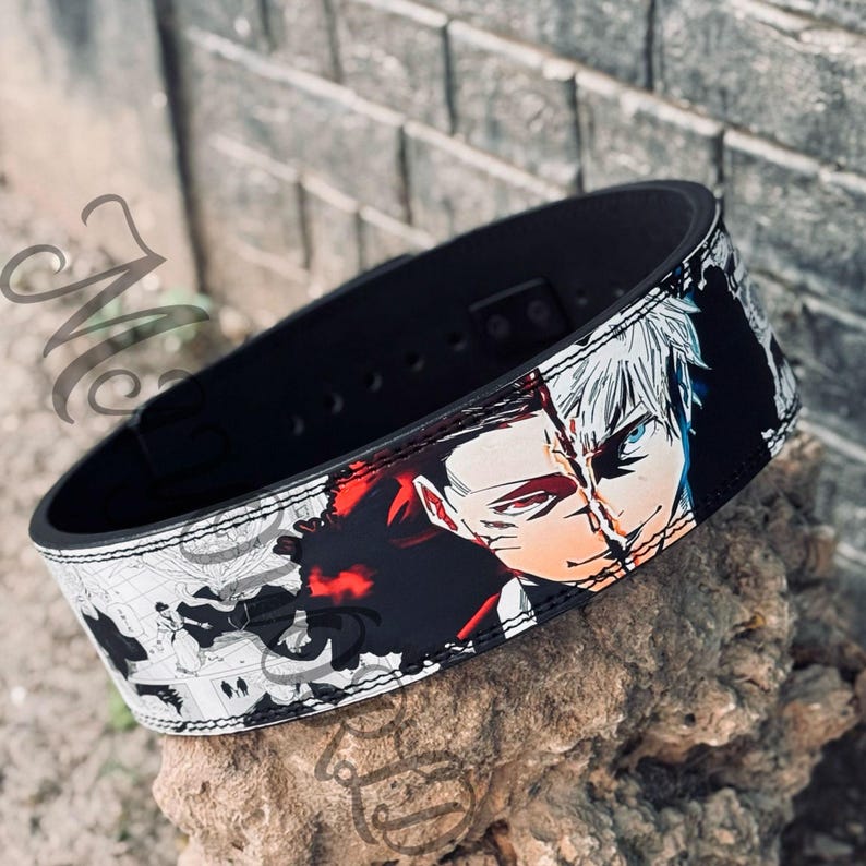 May include: Black weightlifting belt with a white and black anime-style graphic of two characters with red and blue accents. The belt has a stitched edge.