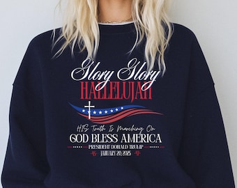 May include: Navy blue sweatshirt with a white graphic print that says "Glory Glory Hallelujah" with an American flag and cross design. The text below the graphic says "His Truth Is Marching On God Bless America President Donald Trump January 20, 2025".