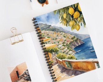 Könnte beinhalten: Aquarellmalerei eines farbenfrohen italienischen Dorfes an einem Kliff mit Blick auf das Meer. Ein Zitronenbaum mit reifen gelben Zitronen hängt über der Szene. Das Gemälde befindet sich auf einem spiralgebundenen Notizbuch.