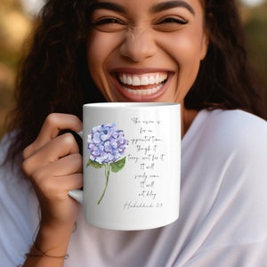 May include: White ceramic mug with a purple hydrangea flower design. The mug has a quote from Habakkuk 2:3 that reads: "The vision is for an appointed time. Though it tarry, wait for it. It will surely come. It will not delay."