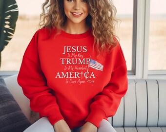Könnte beinhalten: Roter Pullover mit dem Text "JESUS Is My King TRUMP Is My President AMERICA Is Ours Again 2024" und einer Grafik der amerikanischen Flagge.
