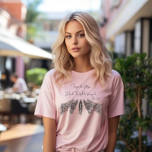 May include: A pink t-shirt with a black graphic that says "Forget the Village I Need the Whole Vineyard My Life".